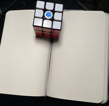 Lined notebook with speed cube separating pages and showing the built-in bookmark.